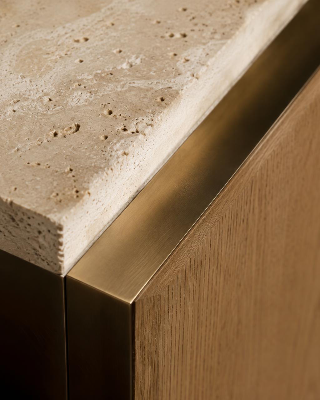 Travertine, bronze and oak meeting at a precise junction