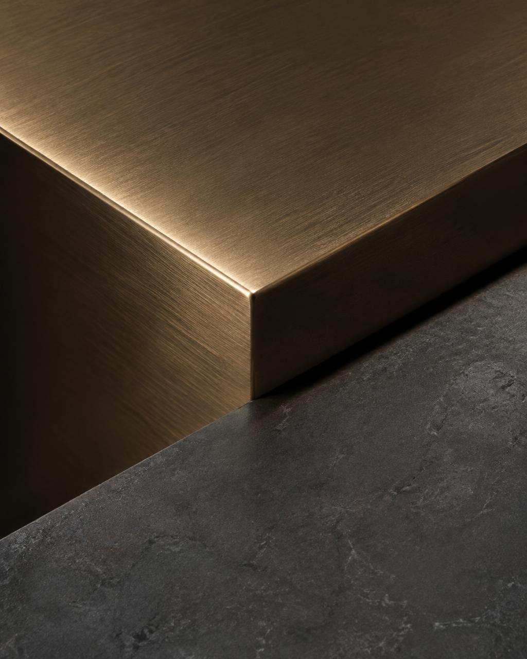Brushed bronze edge meeting honed dark stone